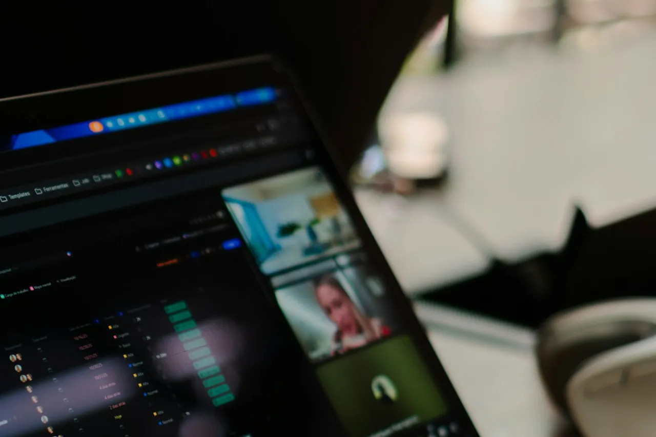 A laptop screen in a dim office shows a video call, with participants' video tiles beside a dashboard.