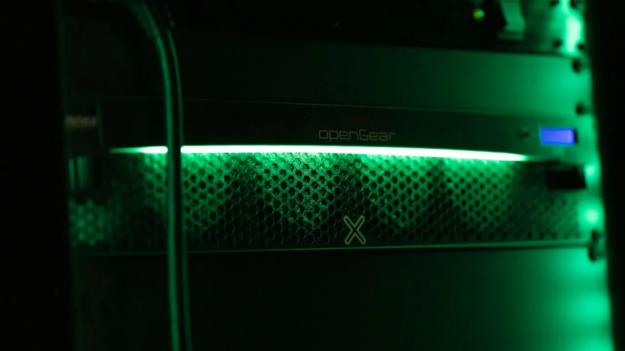 A rack-mounted network appliance glows green in a dark server cabinet.