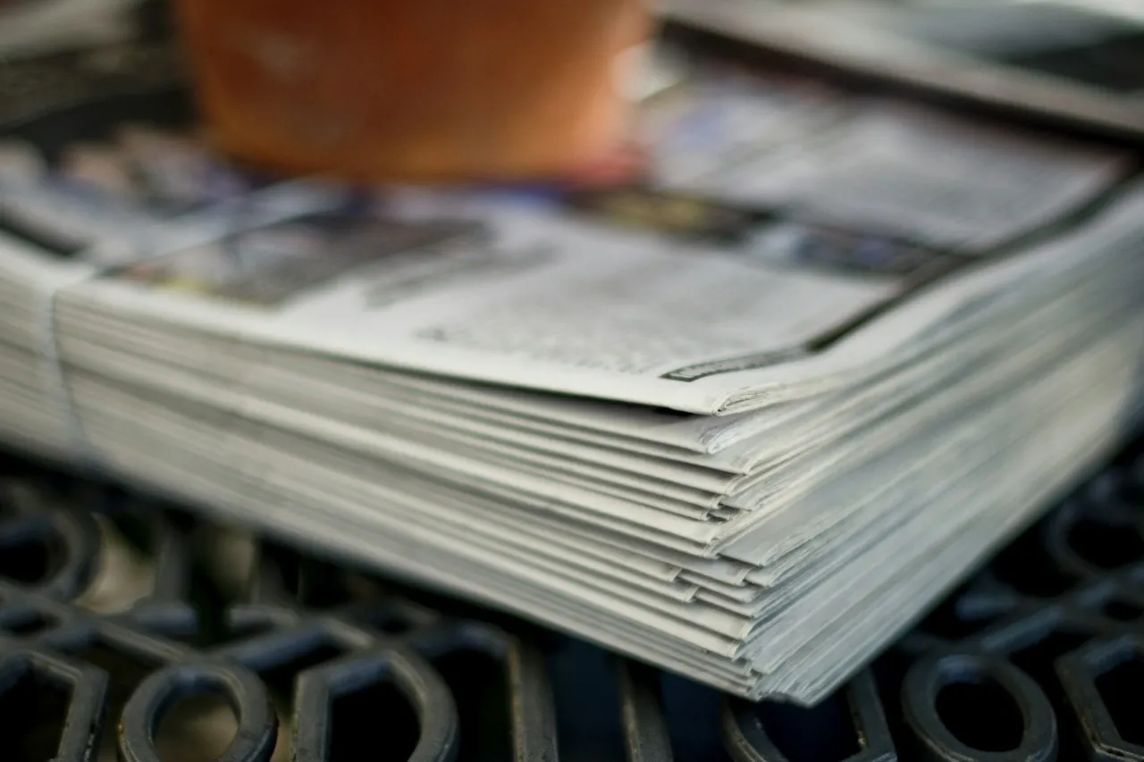 A thick stack of folded newspapers on a table.