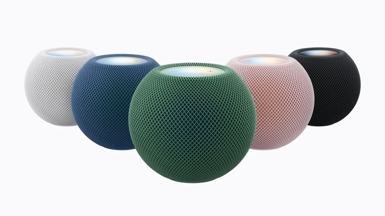 Apple's press image of five HomePod mini 2 speakers. Each is a small sphere covered in mesh fabric with a glowing flat top. They are white, blue, green, pink and black.